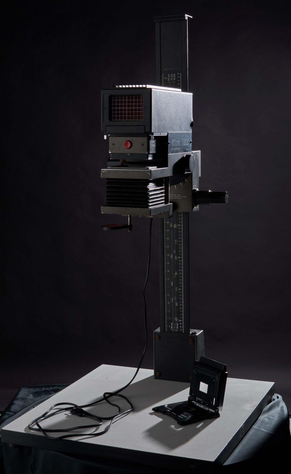 A Durst Enlarger. The top part emits light downwards and hits the table. Under the accordion pleats, you can put the negative film.